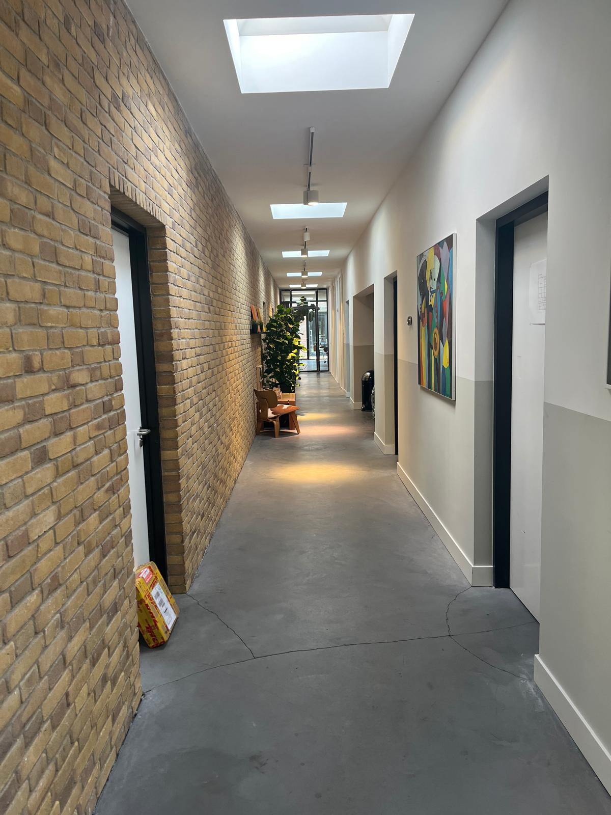 Lange gang met bakstenen muur en deuren aan beide zijden
